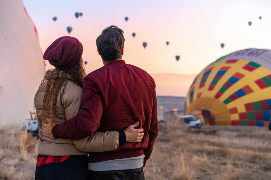 Pareja observando globos aerostáticos al amanecer